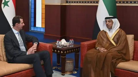 EPA Assad sitting beside Sheikh Mansour bin Zayed Al Nahyan