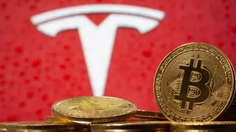 Reuters Representations of virtual currency Bitcoin are seen in front of Tesla logo in this illustration