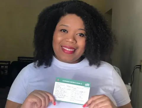 Aline Nogueira Mariano shows her vaccination card