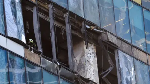 Reuters An emergencies services employee works inside a damaged skyscraper in Moscow. Photo: 1 August 2023