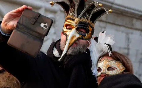 Reuters A masked couple takes a selfie during Carnival celebrations