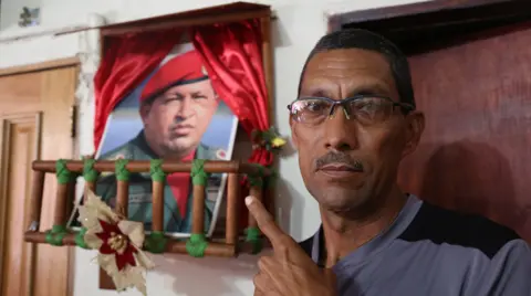 BBC Marcos Lobos points to a shrine to the late president, Hugo Chávez, in his home