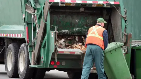 Getty Images Bin man emptying a bin into a lorry