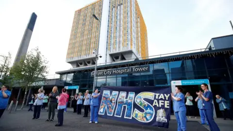 Reuters NHS workers with a banner react at the Nightingale Hospital during the Clap for our Carers campaign in support of the NHS in May