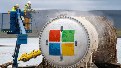 Microsoft Two men power-wash the exterior of the Microsoft data centre capsule