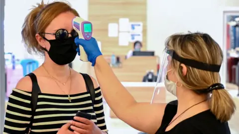 Getty Images A Georgian shop assistant takes a customer's temperature in Tbilisi
