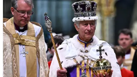 PA Media King Charles III wearing the Imperial state Crown carrying the Sovereign's Orb and Sceptre
