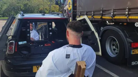 dooo Man getting a hair cut in car park