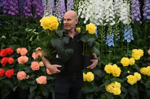 EPA An exhibitor carries delphiniums during preparations for the RHS Chelsea Flower Show 2023 in London, Britain, 21 May 2023.