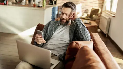 Getty Images Stock image of man on laptop and using smartphone