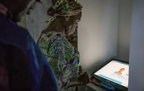 AFP A voter (R) is taught how to use an electronic voting machine by an Independent National Electoral Commission (CENI) agent at the CFP Katuba polling station in Lubumbashi"s Kisale district on December 30, 2018