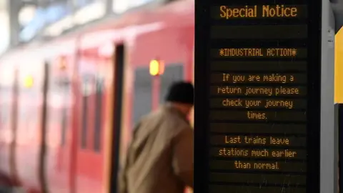 Reuters File photo showing man boarding a SWR train with Industrial Action advice displayed on a noticeboard next to him.