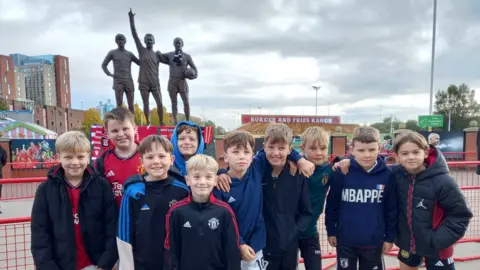 BBC Young football fans in front of statue remembering Sir Bobby Charlton