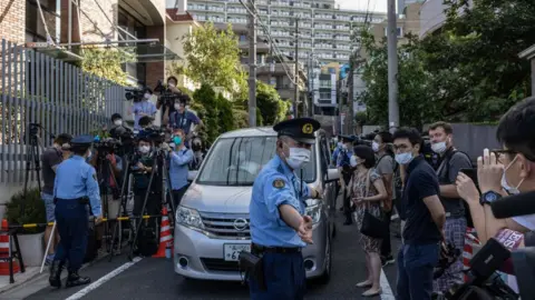 Getty Images Police officers erect a cordon for the media outside the Polish embassy before the departure of a car believed to be carrying Belarus athlete Krystina Timanovskaya to Narita Airport