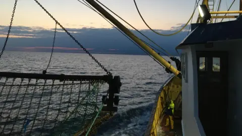 Fishing boat at sea at sunset