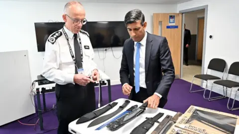 Getty Images Prime Minister Rishi Sunak and Metropolitan Police Commissioner Mark Rowley look at knives and machetes