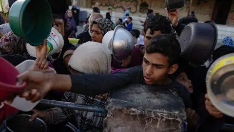 EPA Displaced Palestinians gather to collect food in Rafah on 12 March