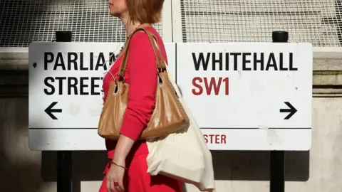 Woman walking past Whitehall sign
