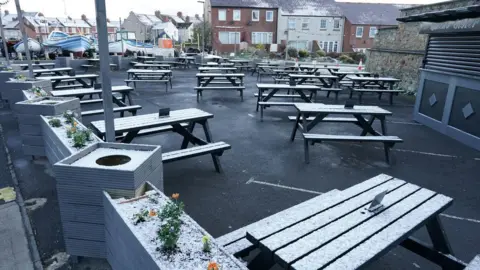 PA Media Snow covers benches in a pub beer garden