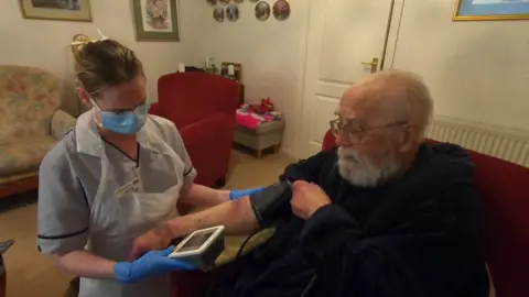 A nurse tends to a patient at home