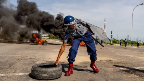 AFP Riot police removing a burnt tyre