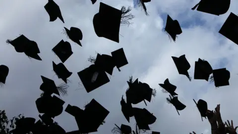 Getty Images University graduands throw their mortar boards into the air