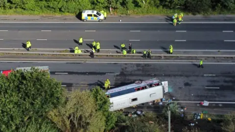 PA Media Emergency services at the scene of a coach crash on the M53 motorway