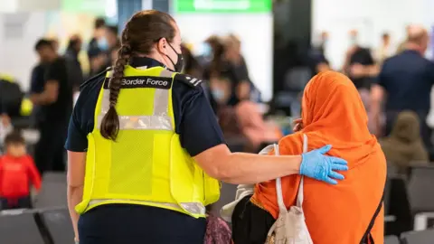 AFP A member of Border Force staff assisting an Afghan refugee on her arrival on an evacuation flight from Afghanistan