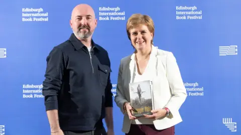 Getty Images Scottish author Douglas Stuart and First Minister of Scotland Nicola Sturgeon attend a photocall at Edinburgh College of Art during the Edinburgh International Book Festival 2021 on August 30, 2021