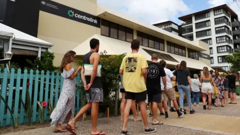 Getty Images People queue to enter a Centrelink welfare office in Queensland in May