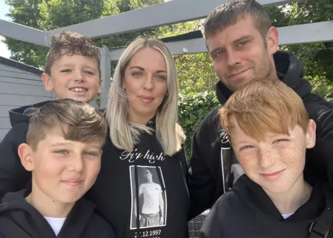 Charley Shepherdson Charley Shepherdson with her family wearing sweatshirts showing Corey Dobbe's photo