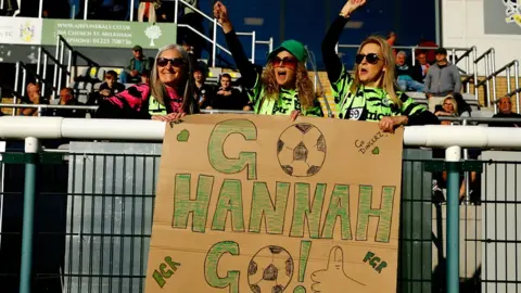 Forest Green Rovers fans hold cardboard with writing go Hannah go written on it