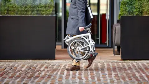 Getty Images Man carrying a fold up bicycle