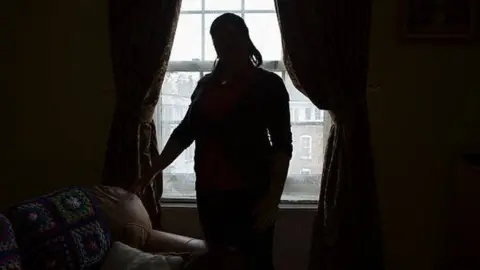 Getty Images Woman in silhouette stares out of window