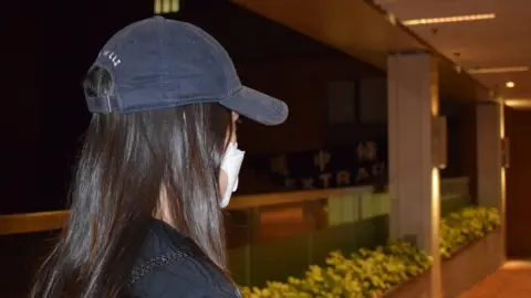 Side view of "Jackie", a student protester, wearing a cap and mask