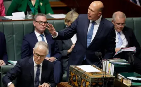 AFP/Getty Images Peter Dutton speaks about a seated Malcolm Turnbull in parliament on Monday