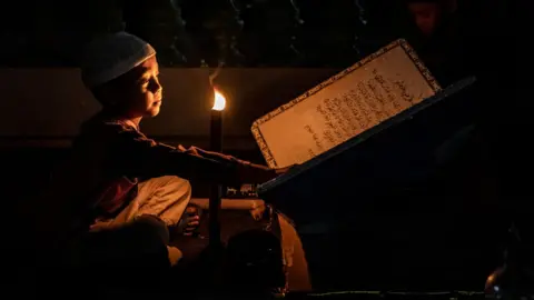 Getty Images An Indonesian Muslim boy holds a torch while reading