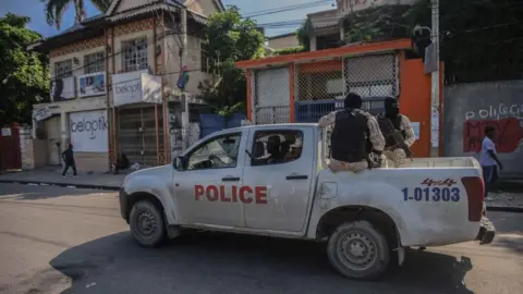 Getty Images Armed police ride in the back of a truck in Port-au-Prince on 18 October