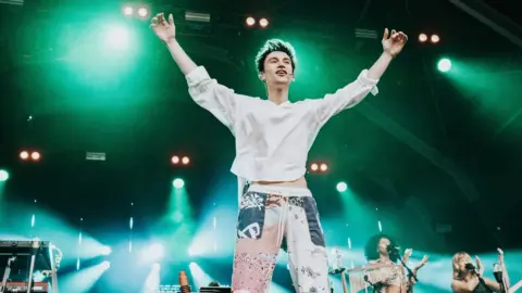 Ania Shrimpton Jacob Collier standing on stage saluting the crowd