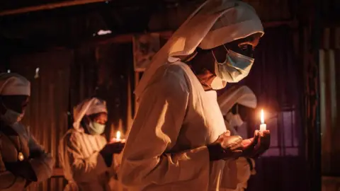 Getty Images Worshippers of Legio Maria wearing face mask as a preventive measure against the spread of COVID-19 attend the Christmas prayer at their church in the Kibera slum of Nairobi, on December 25, 2020.
