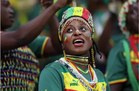 Getty Images Fan wearing colours of the Senegal flag in a crowd of people watching the football.