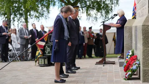 PA Media Princess Anne bowing her head in front of the wreaths laid at the base of the Ulster Tower. 
