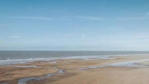 The unspoilt beach of Anderby Creek. The tide is out and water channels cross the beach.