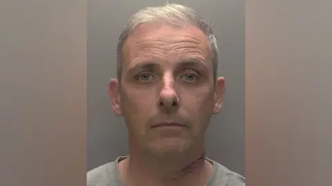 Humberside Police Police mugshot of Anthony McDonald with grey short hair wearing a grey shirt and a cut on his neck