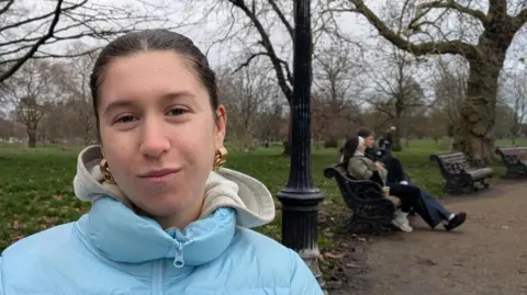 Woman, Kristina Candy, on a park bench. 