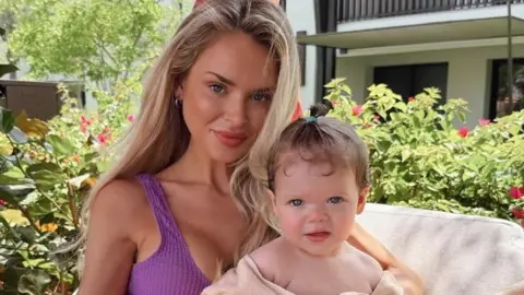 Robyn Baker has long blonde hair and is wearing a purple top. On the right is her daughter who has short brown hair tied in a top-knot.