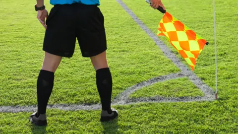 Getty Images Football assistant referee stood on a pitch