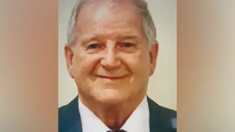 Ray Barron A head and shoulders photo of a man with a white shirt and blue suit