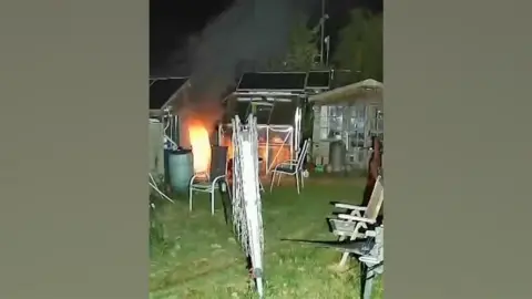 A still from footage showing a fire take hold at a shed in a garden