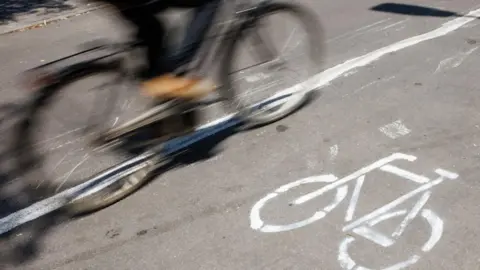 An image of a moving bicycle passing a bicycle sign, which is painted in white on the ground.